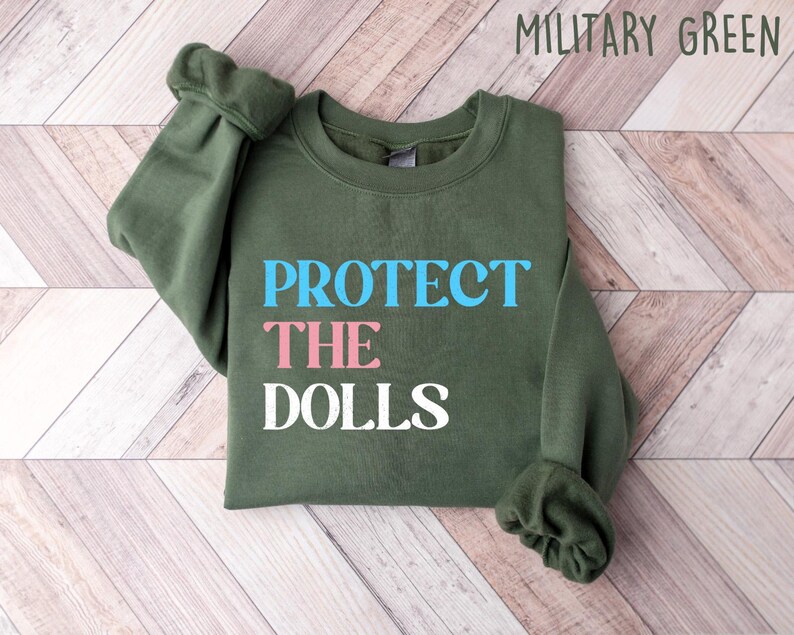 May include: A green sweatshirt with the text "PROTECT THE DOLLS" in blue, pink, and white lettering.