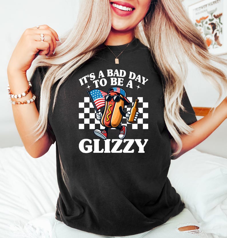 May include: Black t-shirt with a white graphic of a hot dog holding an American flag and a beer. The text on the shirt reads "It's a bad day to be a Glizzy".