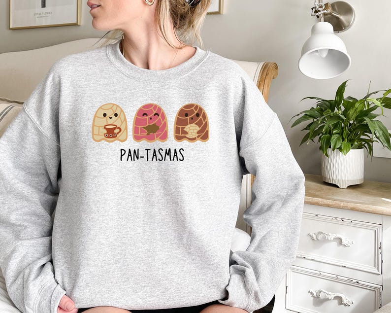 May include: A gray sweatshirt with a graphic of three cartoon pan dulce, or sweet bread, with the text "PAN-TASMAS" below.