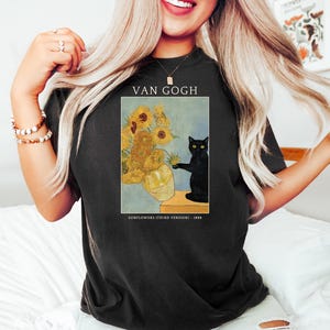 May include: Black t-shirt featuring a print of Van Gogh's "Sunflowers (Third Version)" painting. The artwork includes a vase of sunflowers and a black cat. The text "VAN GOGH" and "SUNFLOWERS (THIRD VERSION) - 1888" are also printed on the shirt.