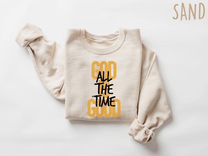 May include: A beige sweatshirt with the text "GOD ALL THE TIME GOOD" printed in black and yellow on the front.