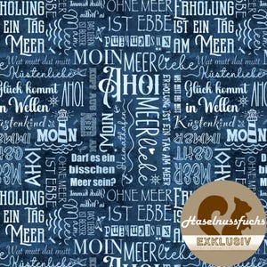 Op de afbeelding: Donkerblauwe stof met witte tekst en nautische illustraties. De woorden "MOIN MEER" en "AHOI" zijn prominent aanwezig, samen met zinnen als "Küstenliebe" en "Glück kommt in Wellen". Een vuurtoren en een zeilboot zijn ook zichtbaar.