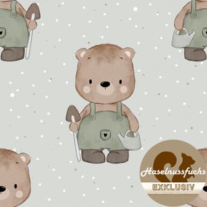 Op de afbeelding: Een herhalend patroon met cartoonberen in overalls, die tuingereedschap vasthouden. De beren zijn lichtbruin met groene overalls en staan tegen een lichtgrijze achtergrond met witte stippen. Een logo met tekst staat rechtsonder.
