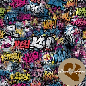 Op de afbeelding: Een levendig graffiti-ontwerp op een bakstenen muur, met kleurrijke gespoten woorden en abstracte vormen in roze, geel, blauw en wit. De stedelijke kunststijl creëert een gedurfde en opvallende esthetiek.