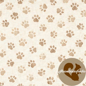 Może przedstawiać: Kremowa tkanina z powtarzającym się wzorem brązowych odcisków łap. Odbitki łap mają różne odcienie, tworząc efekt tekstury. Brązowe okrągłe logo z wiewiórką i tekstem "Haselnussfuchs" znajduje się w prawym dolnym rogu.