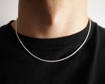 May include: A silver rope chain necklace worn on a person's neck.