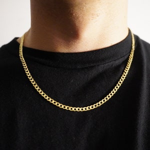 Può includere: Una collana a catena d'oro su una persona che indossa una maglietta nera.
