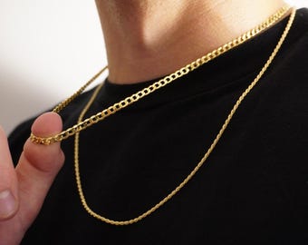 Könnte beinhalten: Zwei goldene Ketten, eine eine Curb-Kette und die andere eine Seil-Kette, als Halskette getragen.