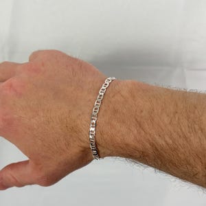 May include: A silver chain bracelet with a mariner link design. The bracelet is approximately 7.5 inches (19 cm) long and is worn on a wrist. The links are oval-shaped and interlock to form the chain.