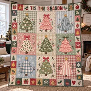 Op de afbeelding: Een doorgestikte plaid met een raster van negen vierkanten, elk met een unieke kerstboomillustratie in verschillende kleuren en patronen. De rand is versierd met kleine feestelijke iconen en de tekst TIS THE SEASON aan de bovenzijde.