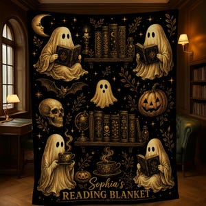 May include: A black blanket featuring gold-toned illustrations of ghosts reading books, a skull, a jack-o'-lantern, a crescent moon, and shelves of books. The text "Sophia's READING BLANKET" is printed in gold at the bottom of the rectangular fabric.