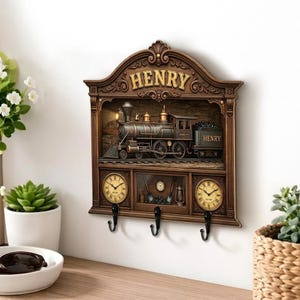May include: A brown wall-mounted organizer featuring a steam locomotive relief with the name HENRY at the top and on the train car. It includes two round analog clocks with Roman numerals, a central display compartment, and three black metal hooks.