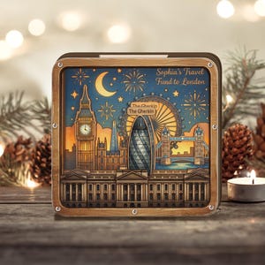 Pode incluir: Obra de arte emoldurada em madeira com uma paisagem urbana de Londres, com marcos icónicos como o Big Ben, a London Eye e o Gherkin. A obra de arte tem um céu noturno com fogos de artifício e uma lua crescente. O texto diz "Sophia's Travel Fund to London."