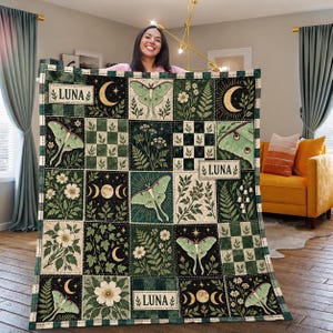 May include: A rectangular quilt featuring a grid of squares with green and cream tones. The design includes illustrations of luna moths, various wildflowers, ferns, ivy, and moon phases. The text LUNA appears in three separate rectangular labels.