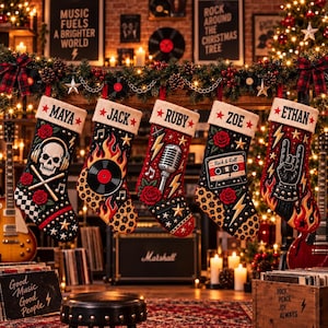 Könnte beinhalten: Fünf Weihnachtsstrümpfe mit weißen Bündchen und den Namen Maya, Jack, Ruby, Zoe und Ethan. Jeder schwarz-rote Strumpf zeigt Rock-Motive wie einen Totenkopf mit Kopfhörern, eine Schallplatte, ein Mikrofon, eine Kassette und eine Handgeste.