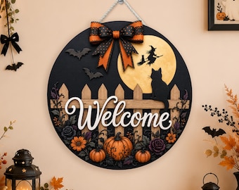 Puede incluir: Un letrero redondo de madera negra con el texto Welcome en blanco, un lazo naranja grande, una luna llena amarilla, la silueta de una bruja en una escoba, un gato negro, una valla de madera, calabazas naranjas y flores moradas oscuras.