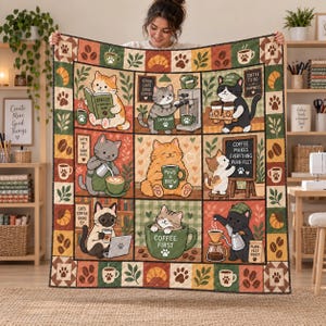 Pode incluir: Uma colcha retangular com uma grade de nove painéis ilustrados retratando gatos em cenários com tema de café. A borda exibe padrões repetidos de grãos de café, pegadas, folhas e croissants em tons de marrom, verde e creme.