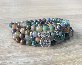 May include: Three beaded bracelets with a variety of earth-toned beads in shades of brown, green, and gray. Each bracelet is strung with round beads and separated by silver-colored metal spacers. A silver charm with a lotus flower hangs from one bracelet.