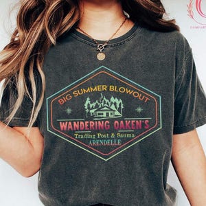 May include: Dark heather Comfort Colors t-shirt with a colorful graphic. The graphic reads "Big Summer Blowout" above "Wandering Oaken's Trading Post & Sauma Arendelle" in a hexagon shape.