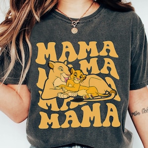 May include: A dark gray t-shirt with a yellow graphic of a lioness and a cub. The graphic says "Mama Mama Mama" in a retro font.