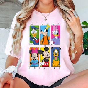 May include: Pink t-shirt with a graphic print of Mickey Mouse and his friends. The text "Mickey and Friends" is printed below the graphic.
