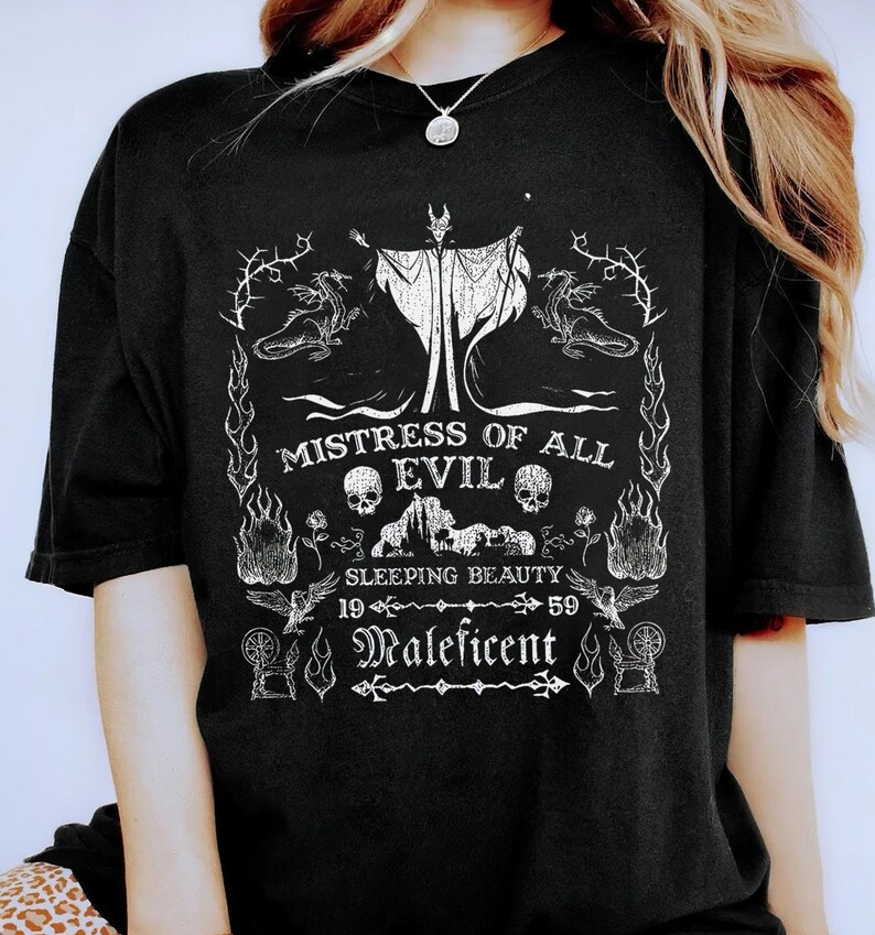 May include: Black t-shirt with a white graphic design featuring Maleficent from Sleeping Beauty. The design includes the text "Mistress of All Evil", "Sleeping Beauty", "19", "59", and "Maleficent".