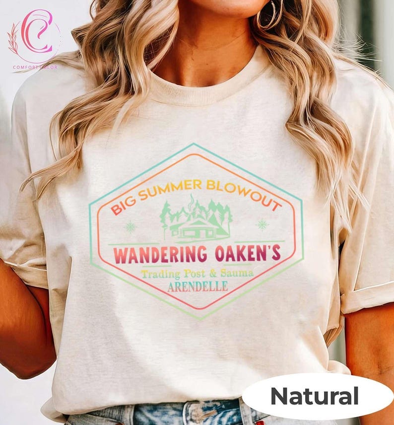 May include: A beige t-shirt with a colorful graphic that reads "BIG SUMMER BLOWOUT" above "WANDERING OAKEN'S Trading Post & Sauna ARENDELLE". The graphic features a cabin, trees, and stars. The word "Natural" is printed at the bottom.