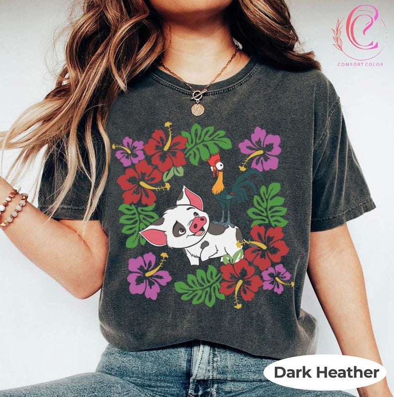 Może przedstawiać: Ciemnoszara koszulka z nadrukiem świni i koguta z kresk&oacute;wki, otoczonych czerwonymi i fioletowymi kwiatami hibiskusa i zielonymi liśćmi. Na dole znajduje się napis "Dark Heather".