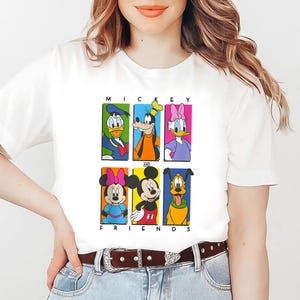 May include: White t-shirt with a colorful graphic of Mickey Mouse and his friends. The graphic features Mickey Mouse, Minnie Mouse, Donald Duck, Goofy, Pluto, and Daisy Duck. The text "Mickey and Friends" is printed below the graphic.