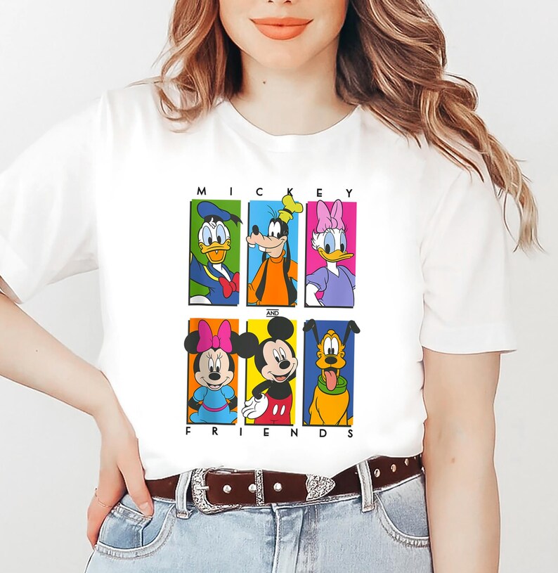 May include: White t-shirt with a colorful graphic of Mickey Mouse and his friends. The graphic features Mickey Mouse, Minnie Mouse, Donald Duck, Goofy, Pluto, and Daisy Duck. The text "Mickey and Friends" is printed below the graphic.