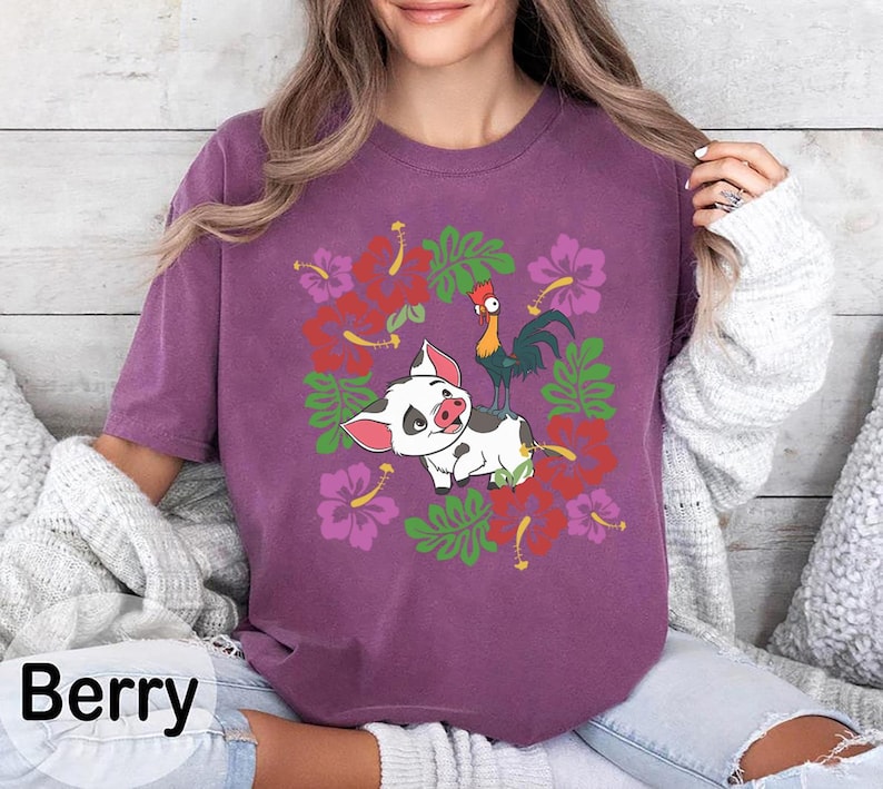 Może przedstawiać: Koszulka w kolorze jagodowym z kresk&oacute;wkową świnią i kogutem z kwiatowymi akcentami. Koszulka ma okrągły dekolt i kr&oacute;tkie rękawy. Słowo "Berry" jest wydrukowane w lewym dolnym rogu obrazu.