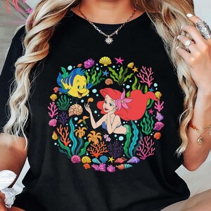 Pu&ograve; includere: Una tazza di ceramica bianca con manico nero e la scritta "But First, Coffee" in nero, in grassetto. La tazza &egrave; appoggiata su una superficie bianca.