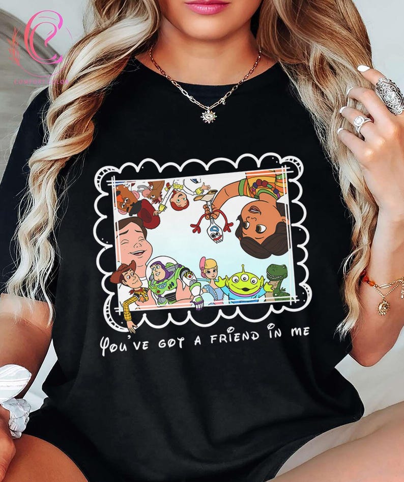 K&ouml;nnte beinhalten: Schwarzes T-Shirt mit einem farbenfrohen Grafikdesign von "Toy Story"-Charakteren in einem wei&szlig;en, wellenf&ouml;rmigen Rahmen. Der Text "You've got a friend in me" ist darunter in Wei&szlig; gedruckt. Ein lustiges, l&auml;ssiges Oberteil.