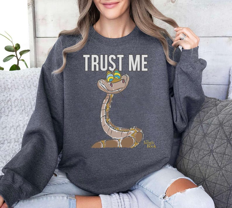 May include: A dark gray sweatshirt with the text "TRUST ME" and a cartoon image of a snake from the Jungle Book. The snake is green and brown with yellow eyes.