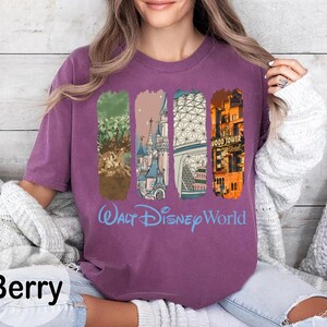 May include: Berry-colored long-sleeve shirt with a graphic of Walt Disney World landmarks. The design includes the Tree of Life, Cinderella's Castle, Spaceship Earth, and the Hollywood Tower Hotel. The words "Walt Disney World" are printed in light blue.