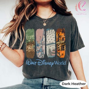 May include: Dark heather gray t-shirt with a graphic featuring four rectangular images of Walt Disney World attractions. The shirt has the words "Walt Disney World" in blue script.