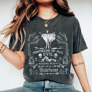 May include: A black t-shirt with a white graphic print of a woman with horns and wings. The graphic includes the text "Mistress of All Evil", "Sleeping Beauty", "19", "59", and "Maleficent".