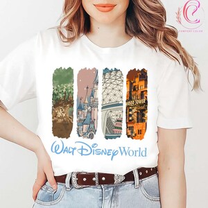 May include: White t-shirt featuring four vertical rectangular designs with illustrations of Walt Disney World landmarks. The shirt includes the text "Walt Disney World" in a light blue script font.