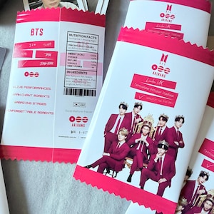 May include: Several pink and white BTS-themed souvenir packages. The packages feature images of the band members in burgundy suits and crowns. Text includes "BTS," "ARIRANG," and "Tottenham Hotspur Stadium."