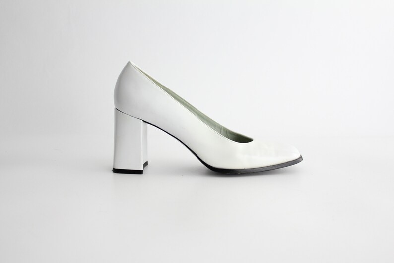 Puede incluir: Zapatos de sal&oacute;n de cuero blanco con tac&oacute;n de bloque cuadrado.