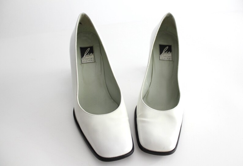 Puede incluir: Par de zapatos de tac&oacute;n de cuero blanco con punta cuadrada y ribete negro. Los zapatos tienen una etiqueta en el interior que dice "Liz Claiborne New York".