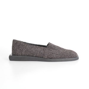 May include: A pair of gray slip-on shoes with a textured fabric upper and a black rubber sole.