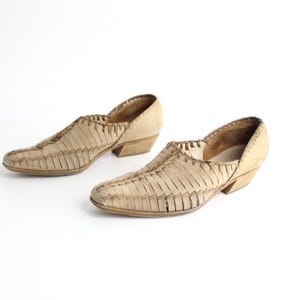 May include: A pair of beige leather shoes with a woven design and a low heel.