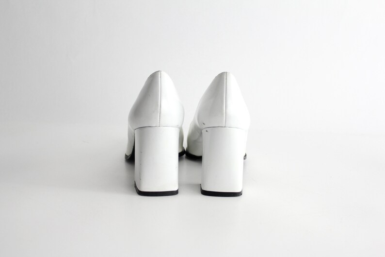 Puede incluir: Un par de zapatos de tac&oacute;n de charol blanco con tac&oacute;n de bloque.