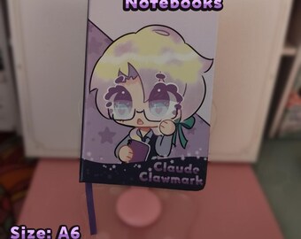 May include: A6 size leatherette paper notebook with a cartoon illustration on the cover. The cover features a character with glasses, a bow, and the text "Claude Clawmark." The notebook has 50 sheets, totaling 100 pages.