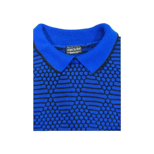 May include: A blue and black patterned knit sweater with a collared neckline. The sweater has a label that reads "objects dot" made in USA.
