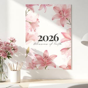 Könnte beinhalten: Ein floraler Wandkunstdruck mit rosa Lilien und dem Jahr 2026. Unter dem Jahr steht der Text "Blossoms of Faith". Der Druck hat einen weißen Rand und hängt an einer hellen Wand.