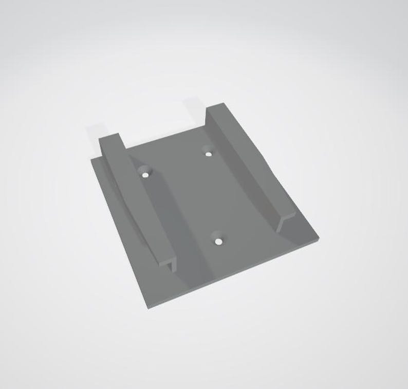 May include: A gray plastic wall mount with two slots and three screw holes.