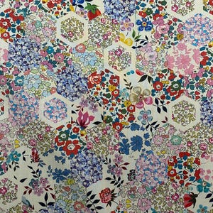 May include: A white fabric with a repeating pattern of colourful flowers and leaves arranged in hexagonal shapes. The fabric has a vintage feel and would be perfect for quilting, crafting, or making clothing.