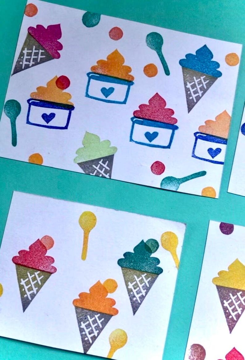 May include: Hand-drawn ice cream cone and sundae illustrations in various colors, including pink, orange, green, and blue, are printed on white cards. Each sundae has a blue container with a heart. Colorful dots and spoons complete the design.